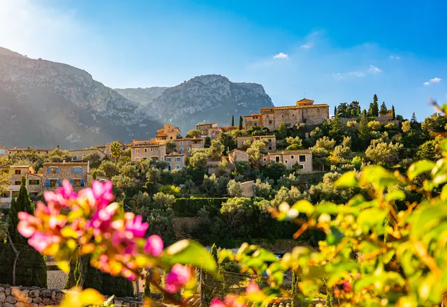 The village of Deià below the Tramuntana mountains, with bougainvillea in the foreground